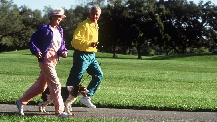 Senior couple jogging in park with their dog