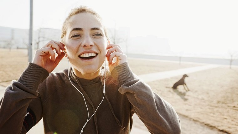 Young woman listening to music with dog in background